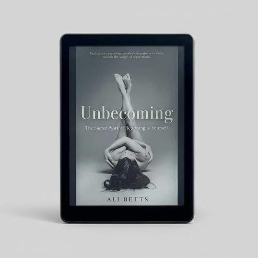 Ebook cover of 'Unbecoming' by Ali Betts on a tablet screen with a marble background.